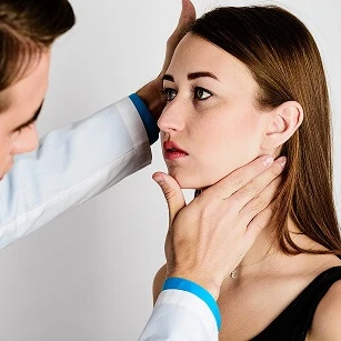 Lekarz ogląda uszy pacjentki w gabinecie lekarskim