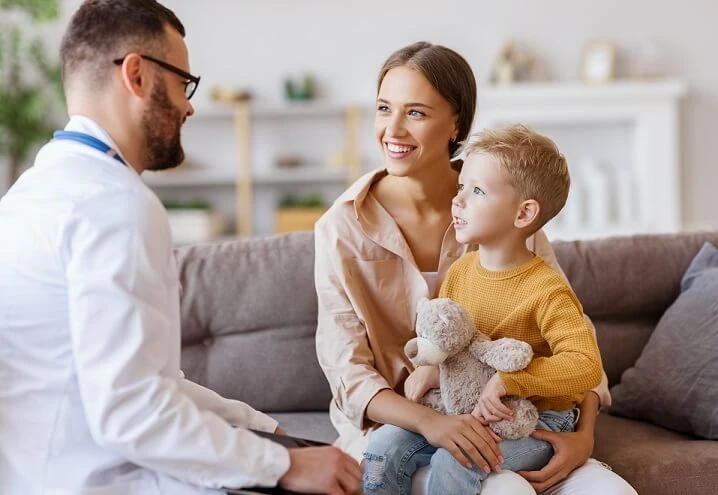 Kobieta siedzi z dzieckiem na kolanach i rozmawia z lekarzem