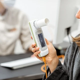 kobieta bada pojemność płuc za pomocą spirometrii