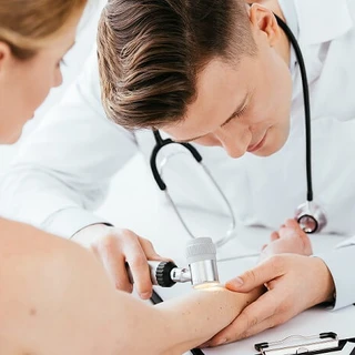 Lekarz bada zmiany skórne w dużym powiększeniu na ręce pacjentki