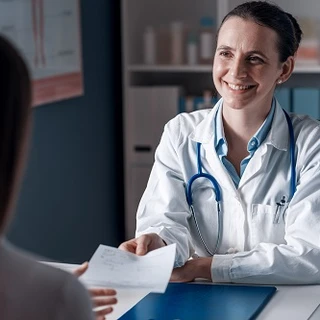 Uśmiechnięta lekarka podaje dokument pacjentce